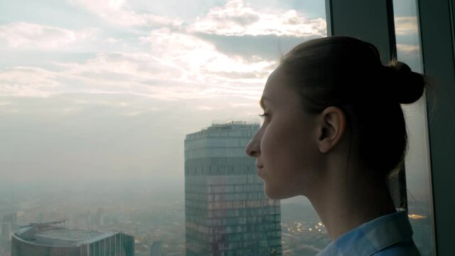 Success, opportunity, sightseeing, discover and future concept. Portrait of pretty woman looking at cityscape through window of skyscraper. Summer time, cloudy, daylight