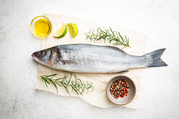 Raw seabass fish with rosemary and spices on white background, top view