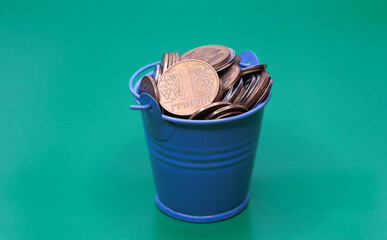 Bucket of coins. Blue bucket with Ukrainian money. Written in Ukrainian: 1 hryvnia.