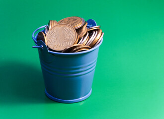 Bucket of coins. Blue bucket with Ukrainian money. Written in Ukrainian: 1 hryvnia. © OLGA RA