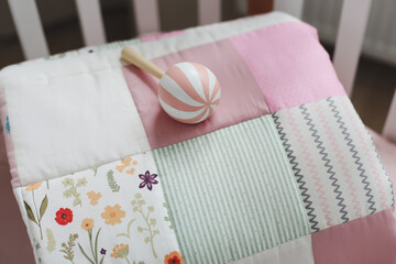 Pink warm patchwork blanket top view. Cozy baby girl cot with blanket. Bedding and textile for children nursery