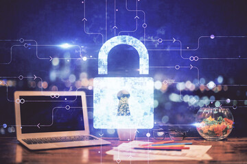 Double exposure of desktop with computer and lock icon hologram. Concept of data safety.