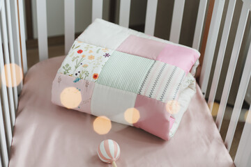 Pink warm patchwork blanket top view. Cozy baby girl cot with blanket. Bedding and textile for children nursery