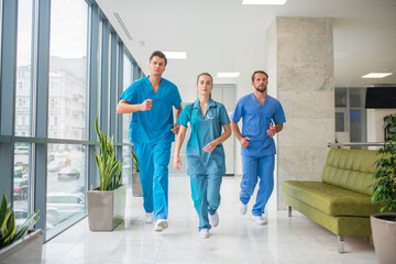 Three doctors running through the hospital corridor being in a hurry
