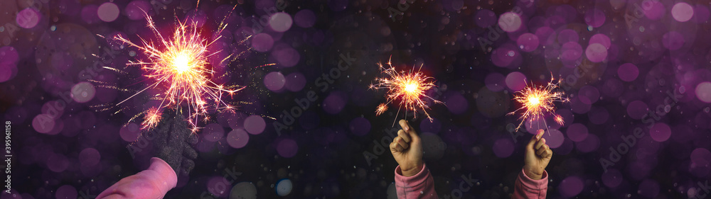 Wall mural Silvester / Party / New Year / Celebration / wedding background - Happy girl and woman holding sparkling sparklers in her hands at dark night with pink bokeh lights