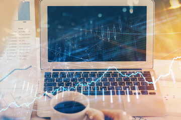 Stock market graph on background with desk and personal computer. Double exposure. Concept of financial analysis.