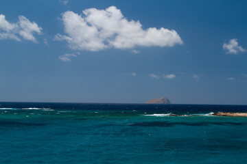  blue clear sea and waves on the surface and rocks and mountains during the day is blue sky in the sky clouds in greece