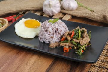 Stir-fried beef basil with fried egg and riceberry rice.
