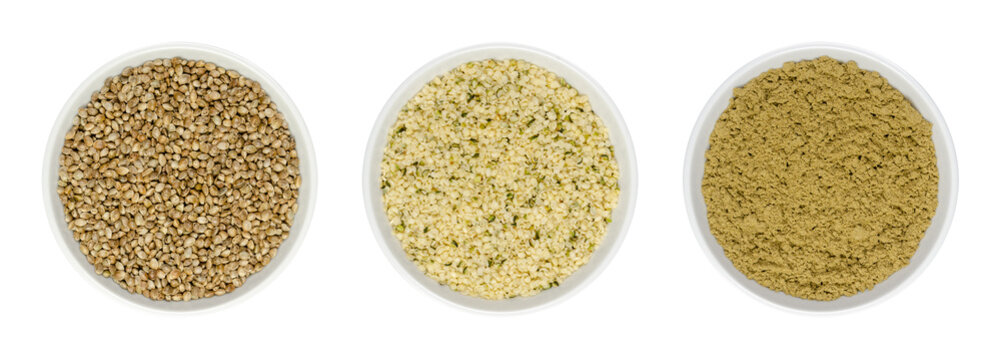 Hemp seeds in white bowls, isolated on white background. Whole, hulled and ground hempseeds. Cannabis sativa fruits. Healthy protein source and meat alternative. Close-up from above, macro food photo.
