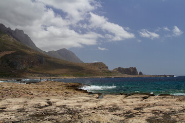 
sea ​​shore and waves on the surface and rocks on the shore during the day and clouds in the sky