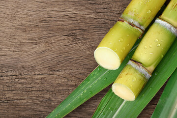 Flat lay (top view) of fresh sugar cane with water droplets on wood background.