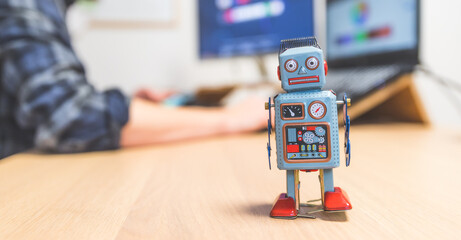 Artificial intelligence concept: Toy robot on office desktop. Metaphor for chatbot, social bot and algorithms