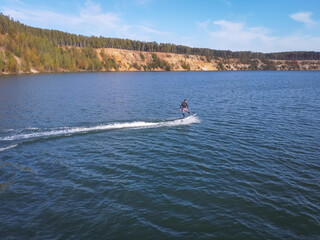 Motosurf Competitor taking corner at speed making a lot of spray. Jet surfing on a water, man riding on jet surfboard. Surfer in motion, summer sport