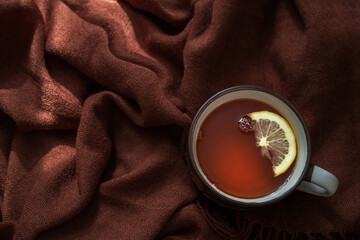 Ceramic cup of hot tea with lemon, on a Brown Woolen Stole. Top view