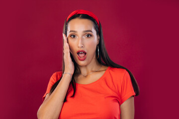 Surprised young woman screaming over red background. Looking at camera