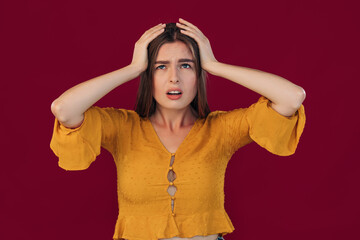 girl with blond hair in a yellow blouse with a hand on her head in pain due to stress. suffers from...