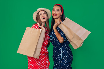 Cheerful girls in casual clothes holding packages with purchases