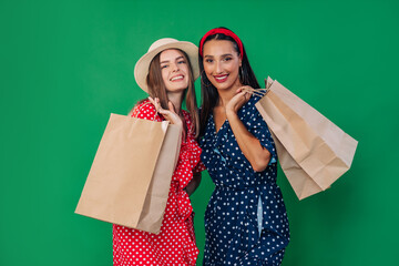 Cheerful girls in casual clothes holding packages with purchases in their hands.