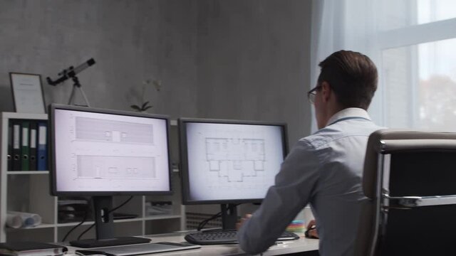 Architect works in loft using drawing board. Workplace of young and serious engineer in modern office.