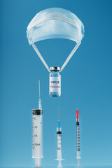 The vaccine antiviral infection was dropped on a parachute over syringes with needles on a blue background.