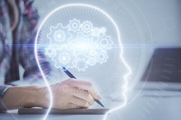 Multi exposure of woman's writing hand on background with brain hud. Concept of learning.