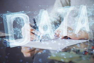Double exposure of writing hand on background with data technology hologram. Big data concept.