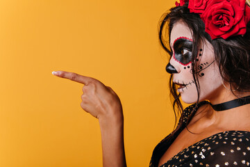 Picture of lady in black top in profile. Girl with skull makeup in surprise shows finger to side