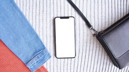 Modern and simple flat lay featuring colourful clothes and accessories with smartphone