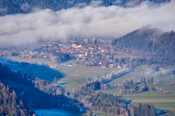 Small bavarian town in the fog, seen from a mountain top