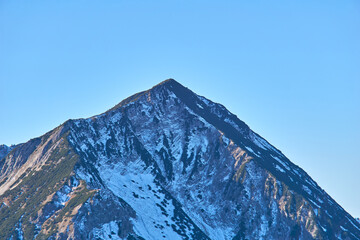 Lonely alpine mountain in front of blue sky