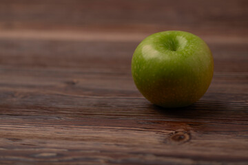 green apple on a brown brushed wooden table