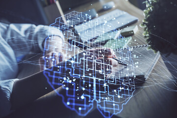 Multi exposure of writing hand on background with brain hologram. Concept of self learning.