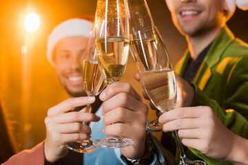  multicultural friends clinking glasses of champagne on blurred black background