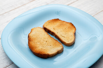 Toasted white bread on a blue plate on a white wooden background. Minimalism.