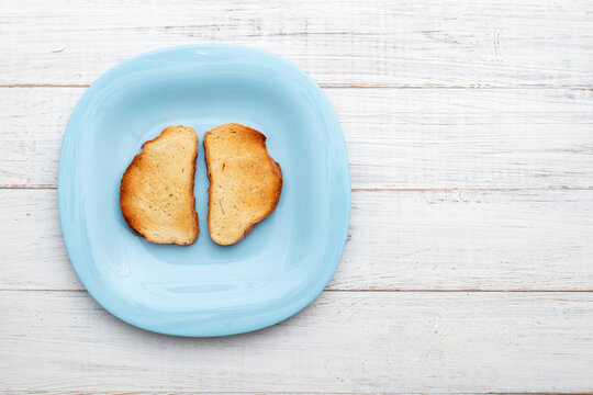 Toasted white bread on a blue plate on a white wooden background. Minimalism.