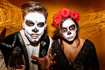 Portrait of mexican couple with skull masks. Girl and guy trying to make awesome face to scare for...