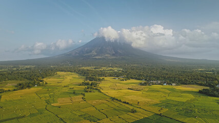 Green meadow at Mayon volcano eruption aerial. Nobody nature landscape of cloudy fog above mount. Tropic scenery of natural beauty of Legazpi countryside, Philippines, Asia. Cinematic drone shot