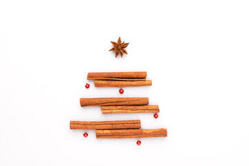Christmas tree made of cinnamon sticks and anise star and decorated with red baubles.