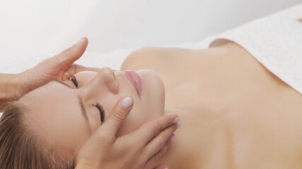 Young, beautiful and healthy woman in massaging salon. Traditional face massage therapy and skin care.