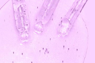 close up macro of pipette dropper with liquid with particles on a purple background