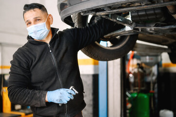 Auto mechanic man with face mask working at auto repair shop. High quality photo