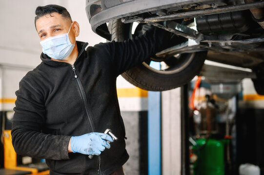 Auto mechanic man with face mask working at auto repair shop. High quality photo