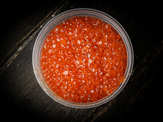 Pink salmon caviar in plastic container. Seafood, delicacies, healthy nutrition. 