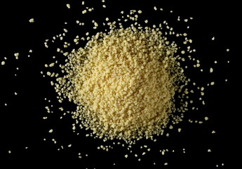 Couscous pile isolated on black background, top view
