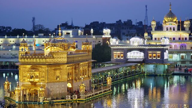 Sikh pilgrims visiting the Golden Temple aka Harmandir Sahib at dusk in Amritsar, Punjab, India. The Golden Temple is the Sikhs' holiest shrine and one of the most important religious sites in India.