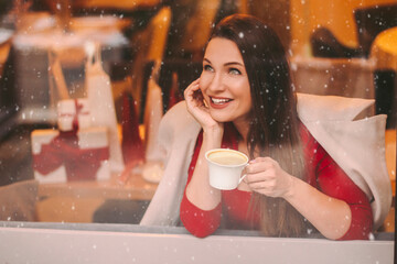 Beautiful happy girl in stylish coat look in window and smile, drink morning coffee in restaurant....