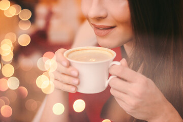 Closeup beautiful young woman hold cup with coffee in hands and smile in restaurant. Attractive happy girl drink tasty coffee in mall cafeteria. Enjoy morning coffee break in cafe, winter hot beverage
