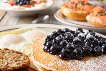 A closeup view of a pancake breakfast plate featured with several other breakfast and brunch plate on a table.