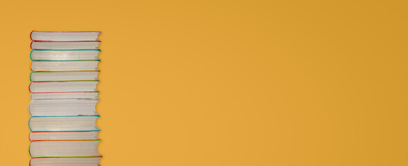 Tall stack of colorful books at gradient yellow background with copy space for text. Concept...