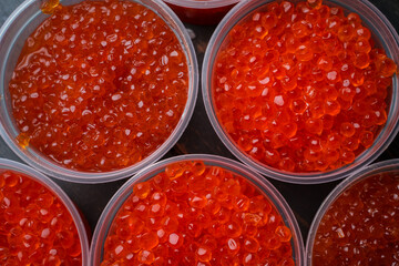Pink salmon caviar and chum salmon caviar in plastic containers. Seafood, delicacies, healthy nutrition. 